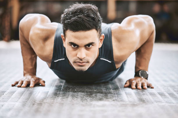 istock Serious fit man about to do a pushup. Young strong trainer working out. Muscular bodybuilder on the floor of a gym. Focused trainer ready to workout on his body. Young man working out 1399396476
