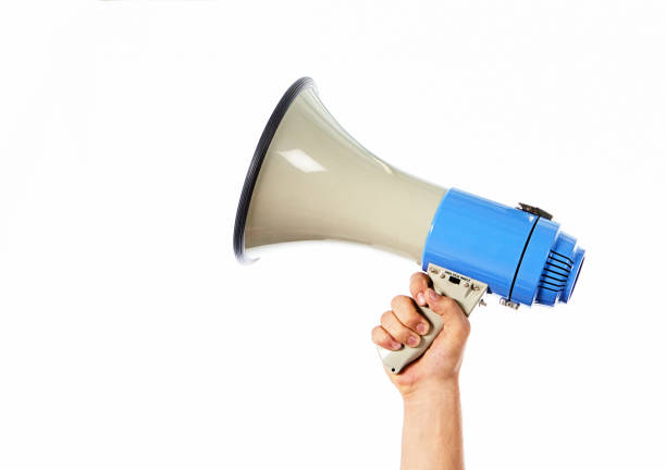 istock Woman's hand holding a megaphone up high against a white background with copy space 1399397462