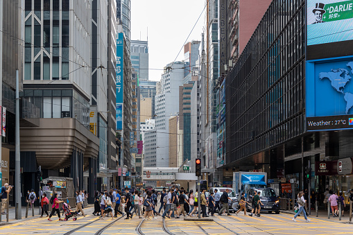 Hong Kong - May 26, 2022 : Pedestrians walk past the Des Voeux Road Central in Central, Hong Kong. Des Voeux Road Central was named after the 10th Governor of Hong Kong, Sir William Des Vœux.