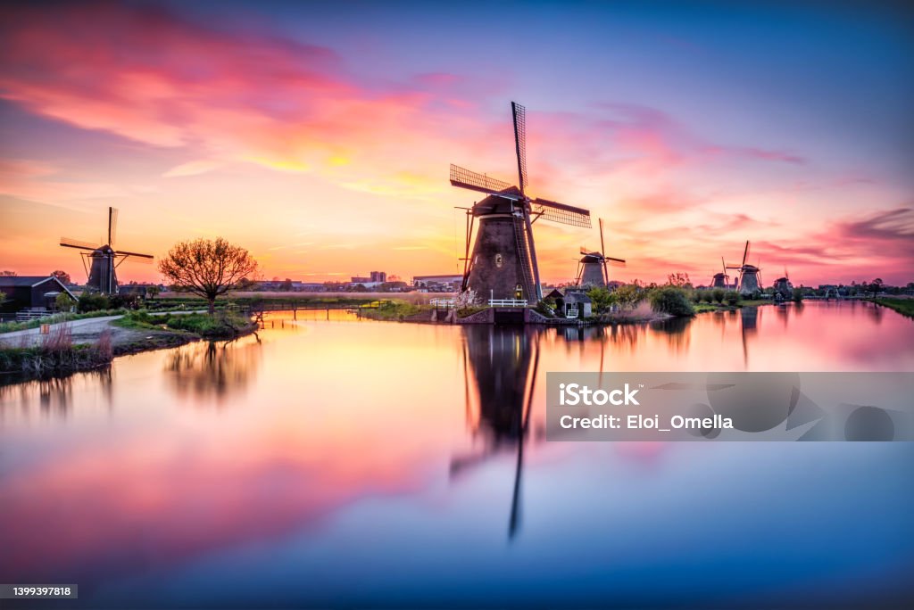 amazing sunset and Windmills at Kinderdijk in Holland. Netherlands Netherlands rural lanscape with windmills at famous tourist site Kinderdijk in Holland on sunset with a candid dramatic red sky reflected on water Netherlands Stock Photo