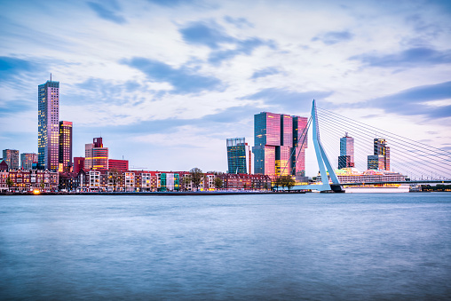 Long exposure photo of Erasmus Bridge, skyscrappers and Ferry in Rotterdam at Dusk, Netherlands