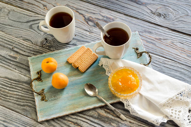 Cup with tea, biscuits, apricot jam on a wooden table close-up