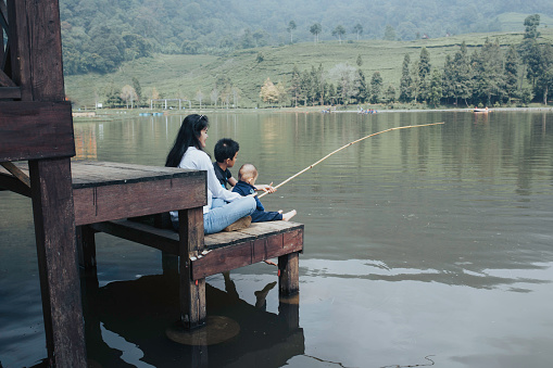 asian mother and his sons fishing at morning in a lake