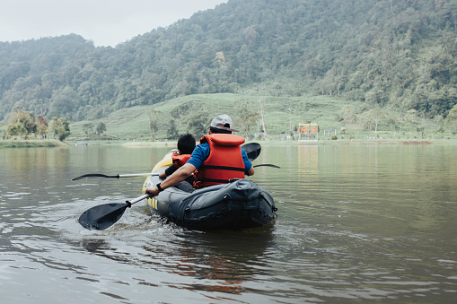 young boy and his father enjoy lake kayaking
