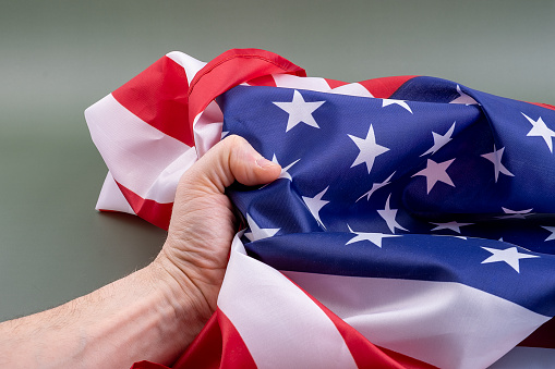 Fist gripping a United States flag tightly on a green background. Concept of the strength of the people.