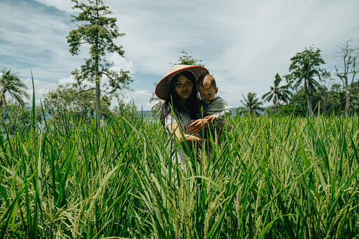 An adult woman and a toddler, a mother and son in a rice paddy field