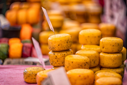 Close up wheels of hard gouda cheese with spices in the market store
