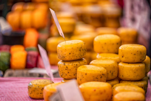 Close up wheels of hard gouda cheese in the market Close up wheels of hard gouda cheese with spices in the market store cheese market stock pictures, royalty-free photos & images
