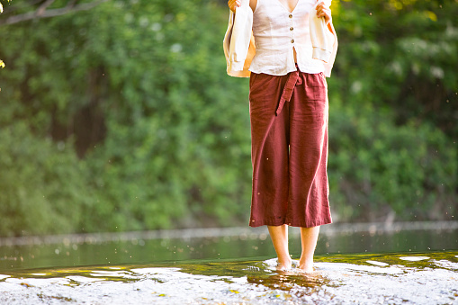 Low Section of Young Woman Standing Barefoot in River.