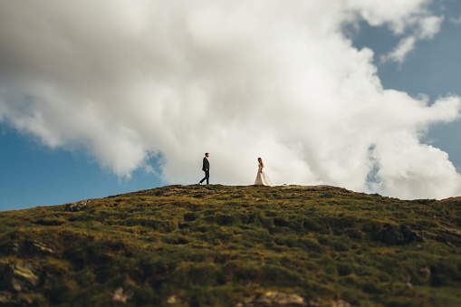 Groom going to meet the bride on a green hilltop. Summer style. Wedding travel.