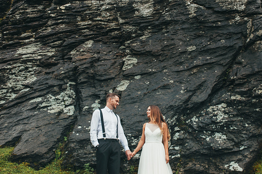 Beautiful newlyweds on their wedding day posing on a stone background, mountain landscape. Wedding travel.