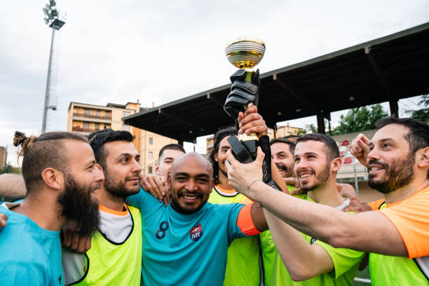 Team players are touching their trophy to celebrate together Team players are touching their trophy to celebrate together. They just won the tournament. soccer team captain stock pictures, royalty-free photos & images
