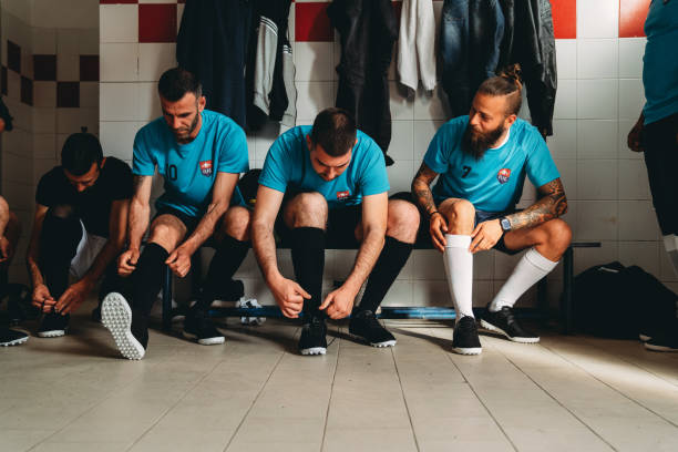 サッカーチームの選手が試合前に更衣室で準備をしている - 着替え室 ストックフォトと画像