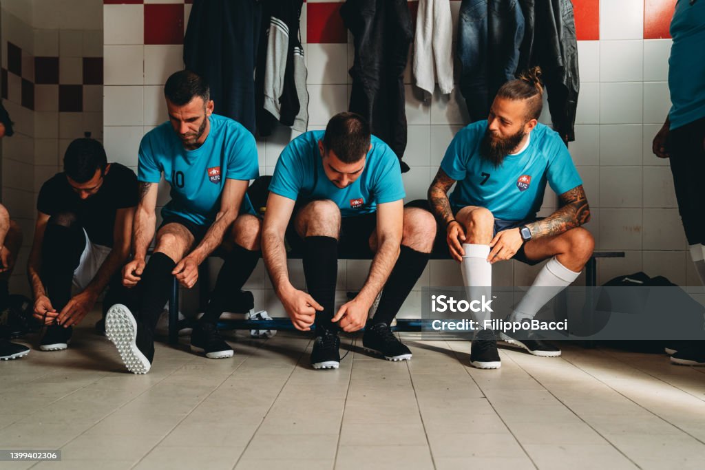 Soccer team players are getting ready in the changing room before the match Soccer team players are getting ready in the changing room before the match. They are dressing. Locker Room Stock Photo