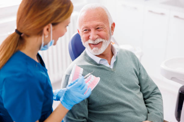 Dentist explaining procedure to patient on plastic jaw model stock photo