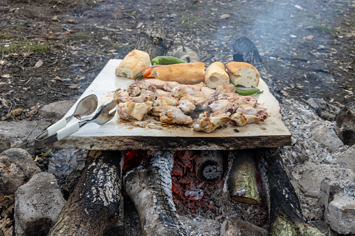 Grilled chicken meat on marble stone in wood fire in nature