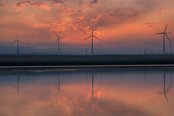Windmills windpower turbines near lake before sunrise with reflection in water landscape\
