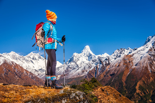 Female trekker standing on the top of a mountain and admires view of Mount Everest, Lhotse and Ama Dablam in Mount Everest National Park.