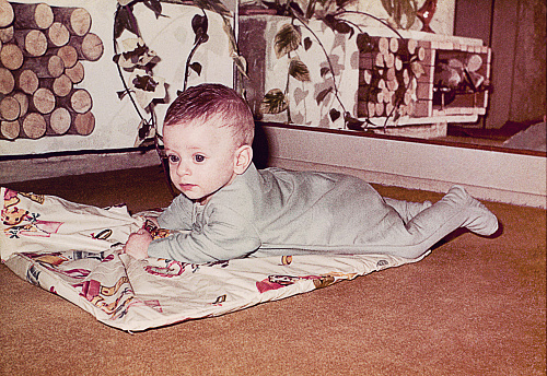 A vintage grainy image of a cute baby boy laying down at home. Vintage photo from the sixties.