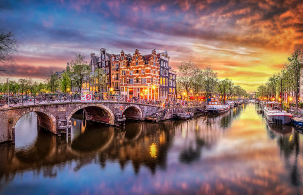 Panoramic view of the historic city center of Amsterdam. Traditional houses and bridges of Amsterdam town. A romantic evening and a bright reflection of houses in the water Sunset in Amsterdam. Panoramic view of the historic city center of Amsterdam. Traditional houses and bridges of Amsterdam town. A romantic evening and a bright reflection of houses in the water. European travel to the historic city. Europe, Netherlands, Holland solar street lights stock pictures, royalty-free photos & images