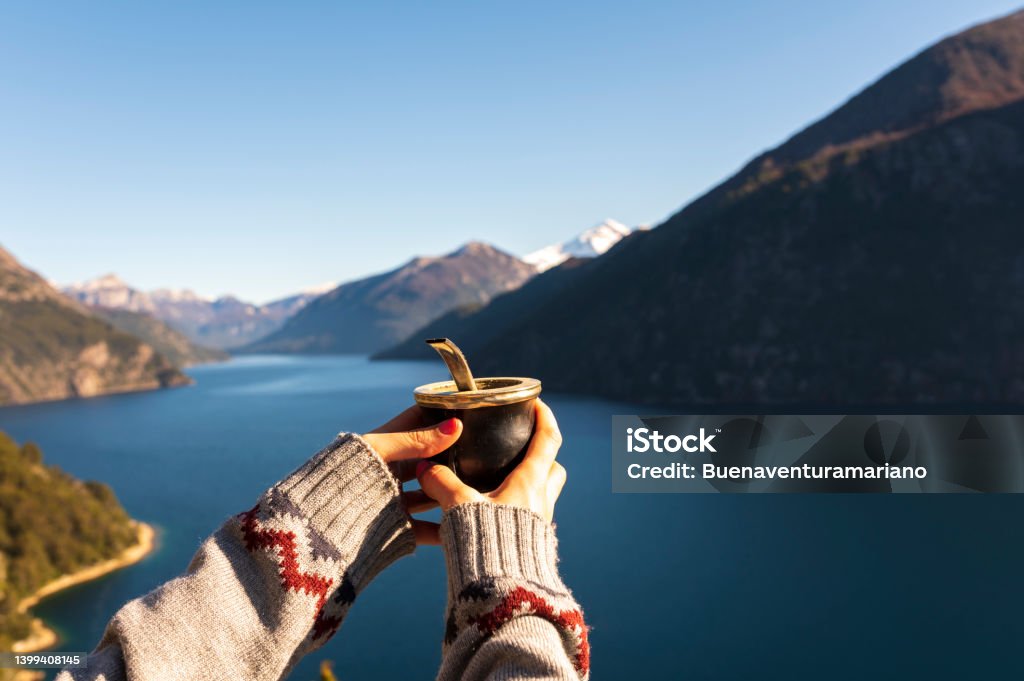 Young woman drinking a mate and contemplating the landscape totally relaxed. Woman enjoying some delicious warm Mates, while contemplating the landscapes of Bariloche during her vacations. Argentina Stock Photo