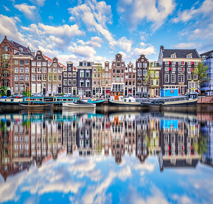 reflection in Amsterdam Singel canal with typical dutch houses and houseboats during morning, Holland, Netherlands.
