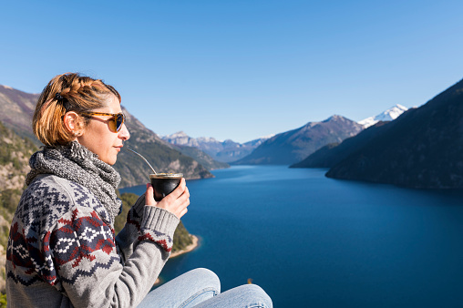 Woman enjoying some delicious warm Mates, while contemplating the landscapes of Bariloche during her vacations.
