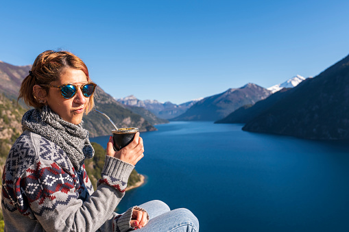 Woman enjoying some delicious warm Mates, while contemplating the landscapes of Bariloche during her vacations.