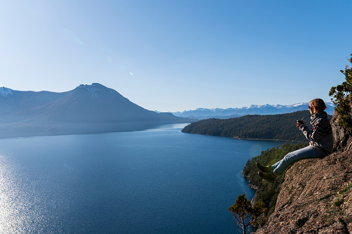 Woman enjoying some delicious warm Mates, while contemplating the landscapes of Bariloche during her vacations.