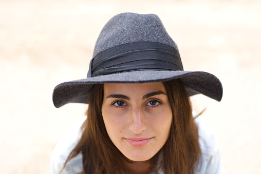 Close-up portrait of pretty smiling young lady with natural skin without makeup and gray hat looking at camera. Female woman concept.