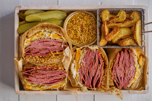 Enormous sandwiches with pastrami beef in wooden box. Served with baked potatoes, pickles Enormous sandwiches with pastrami beef in wooden box. Served with baked potatoes, pickles and french mustard. Top view, flat lay. reuben sandwich stock pictures, royalty-free photos & images