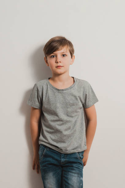 istock a boy with scared face standing by the white wall, looking at camera 1399417029
