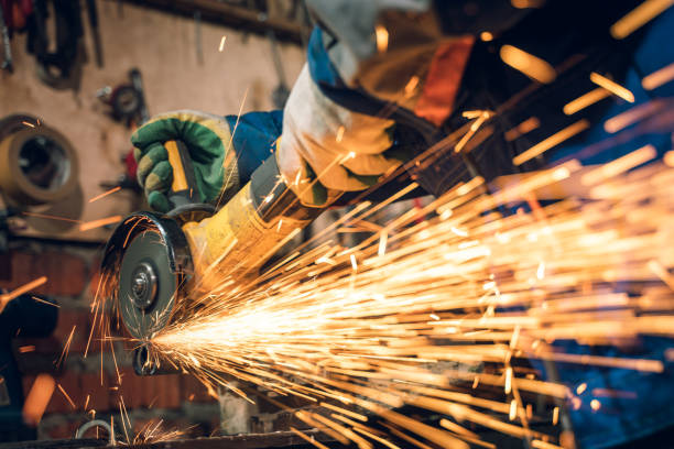 istock Locksmith in special clothes and goggles works in production. Metal processing with angle grinder. Sparks in metalworking 1399418213