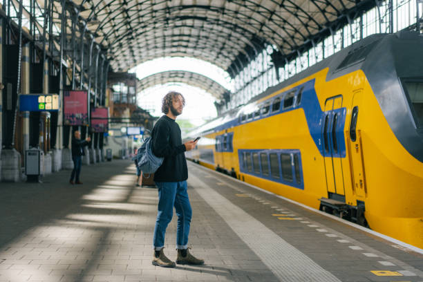 man waiting for the train on railway station - trein nederland stockfoto's en -beelden