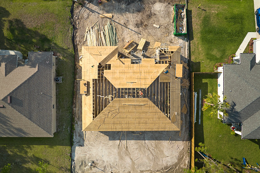 Aerial view of suburban private house wit wooden roof frame under construction in Florida quiet rural area.