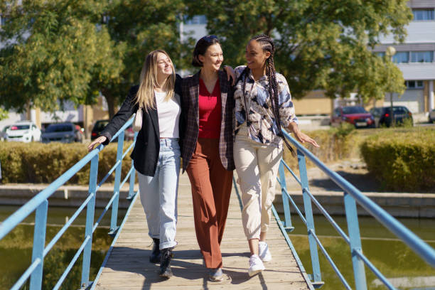 istock Smiling diverse friends hugging while strolling on narrow footbridge 1399420973