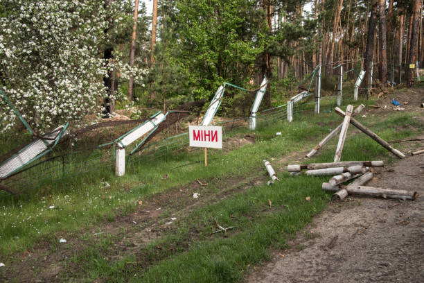 schild "minen" am straßenrand mit einem zaun, der von militärischer ausrüstung durchbrochen wurde - spring tree orchard forest stock-fotos und bilder