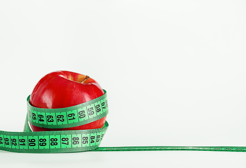 Measuring green ribbon wrapped around a red apple as a symbol of diet and healthy life