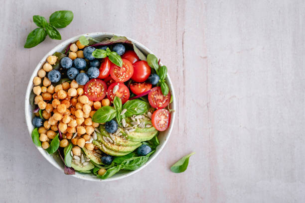 Chickpea salad bowl Overhead view of a bowl of colorful vegan chickpea salad located on the left side on a minimal background salad bowl stock pictures, royalty-free photos & images