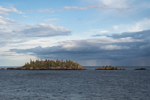 A rain storm moves across the horizon of Lake Superior.  There are two small islands in the foreground of the scene.