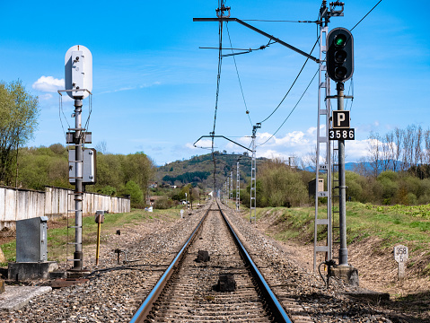 High luminous railway signals located in the middle of the track and their corresponding ASFA beacons located between the rails above the sleepers on a straight line that is lost in the mountains