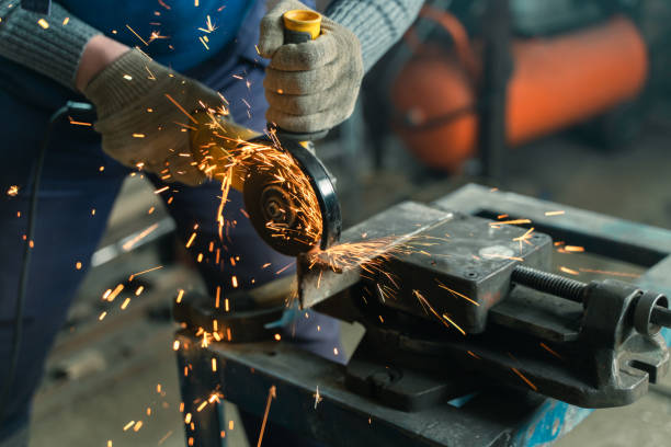 istock Locksmith in special clothes and goggles works in production. Metal processing with angle grinder. Sparks in metalworking 1399430511