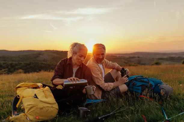 Hiking couple resting after walking and drinking hot beverage stock photo