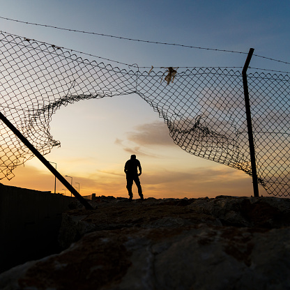Refugee man running behind fence