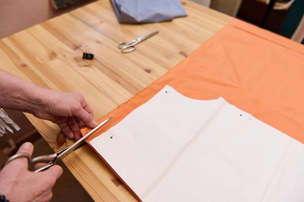 istock Close-up hands of a fashion designer using scissors cuts sewing pattern in fabric while creating new collection of handmade clothes in tailor atelier 1399440840