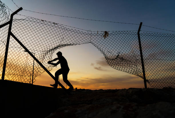 istock Refugee man running behind fence 1399441849