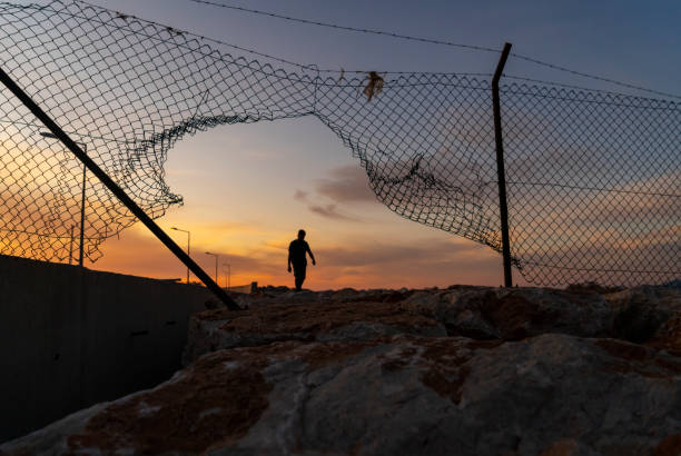 istock Refugee man running behind fence 1399441865