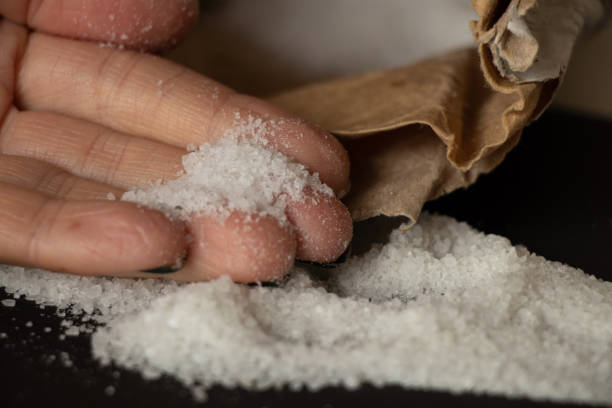 istock Rock salt close-up scattered on a black background and a woman's hand,salt 1399441938