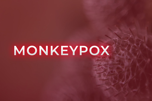 Monkeypox virus. Red background. Outbreak concept. Virus transmitted to humans from animals. Monkeys may harbor the virus and infect people. New pandemic. Word monkeypox. Blurred. Molecular. Virus.