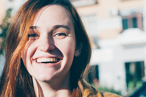 Freckled brunette young woman enjoying sunny day, natural make-up. Street fashion, genuine smile. Pretty look, clean perfect skin. Close-up view. Emotion, mimic, state of mind concept